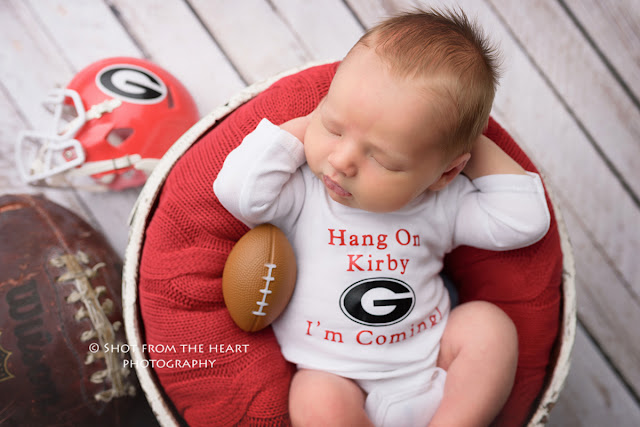 newborn baby with UGA helmet, football, sleeping in bowl photography