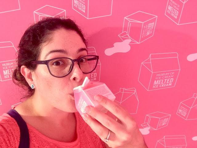 E. L. Lane drinking from a pink milk carton in front of a wall with a pink milk cartons print