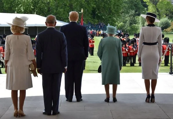 Melania Trump is wearing a custom white crepe dress with navy details by Italian fashion house, Dolce & Gabbana. Queen Elizabeth