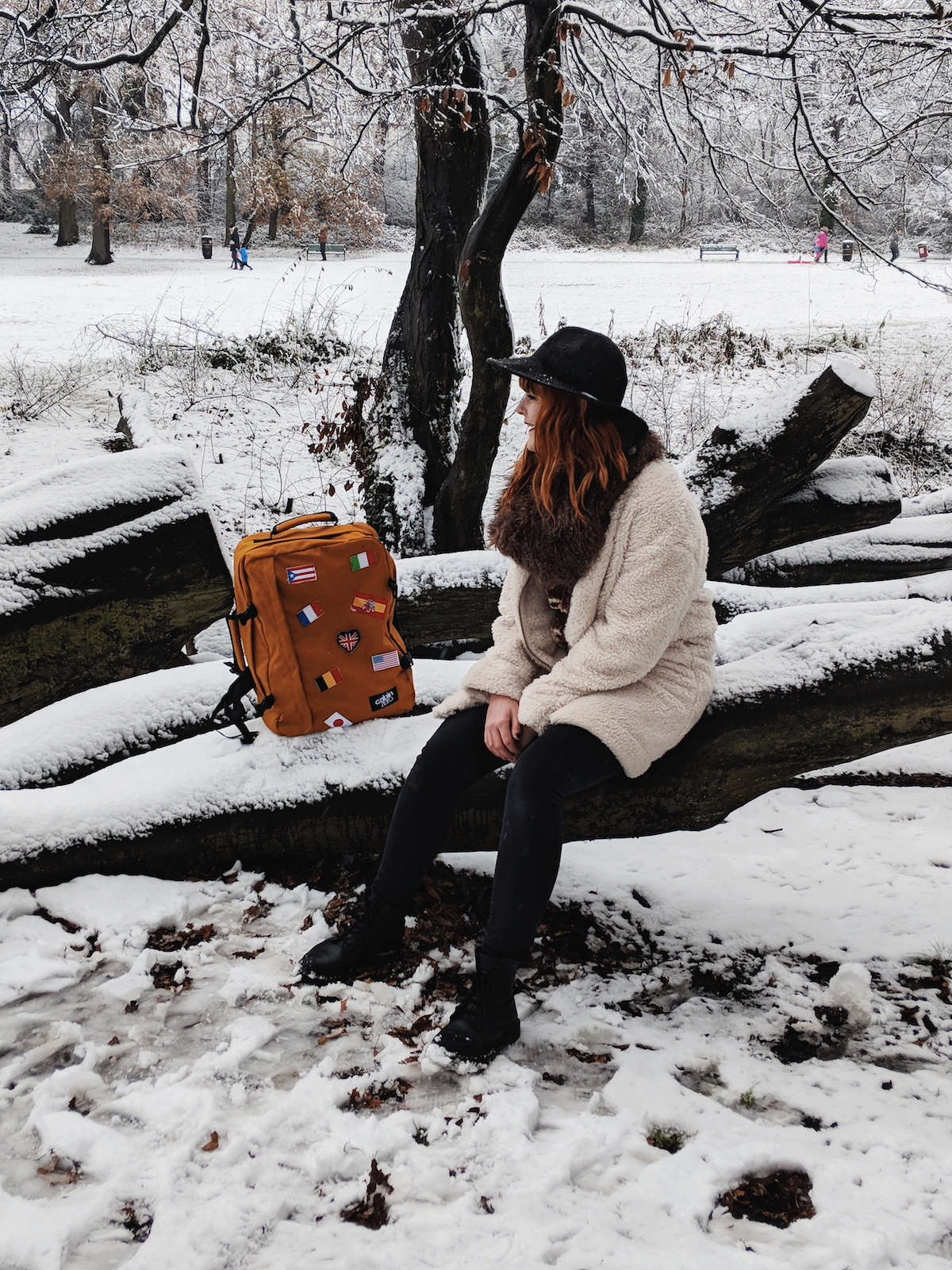 Travel blogger, Leigh Travers, sits amongst a snowy forest scene with her Cabin Zero rucksack