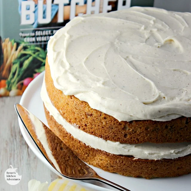 Parsnip Ginger Layer Cake with Browned Butter Frosting on cake platter with book in background