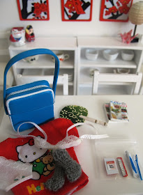 Modern dolls' house miniature dining table with a carry on bag, toiletries and spare underwear on it.