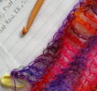 close up of silk mohair scarf in progress with a bamboo crochet hook resting next to it on top of some handwritten pattern notes