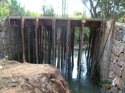 Construção do muro de pedra com pedra bruta para a base da construção da ponte de concreto na entrada da empresa em Atibaia-SP.
