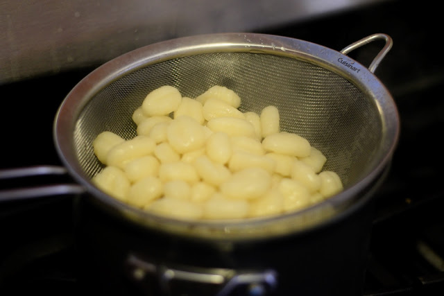 The fully cooked gnocchi in a strainer.  