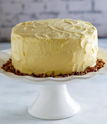 This lovely cake is the perfect combination of flavors and textures. The warm maple syrup blends perfectly with pecans for an out of this world cake, the maple frosting is amazing too! Dessert is served and it's delicious! round maple cake on white pedestal