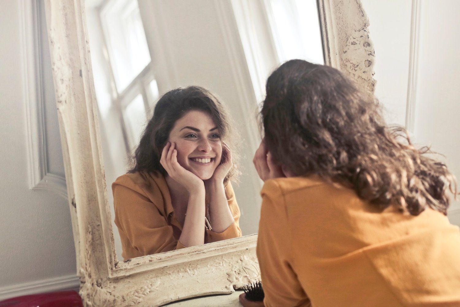 girl is smiling to her reflection in the mirror