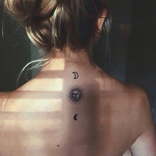 Um personificada sol fica entre um par de luas crescentes em volta da tatuagem.