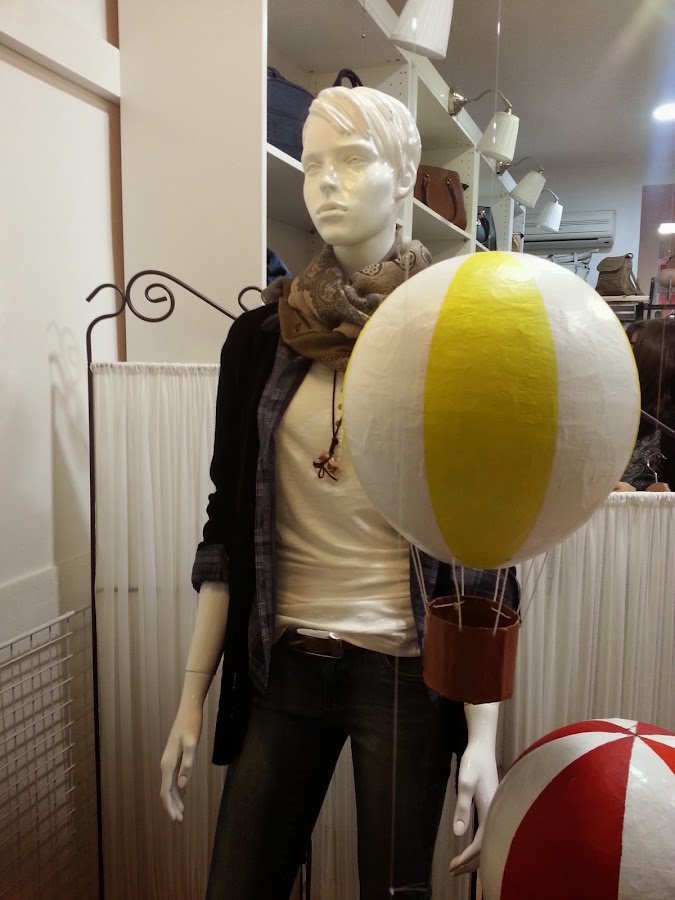 Globo amarillo y rojo, en escaparate de ropa, con maniqui femenina