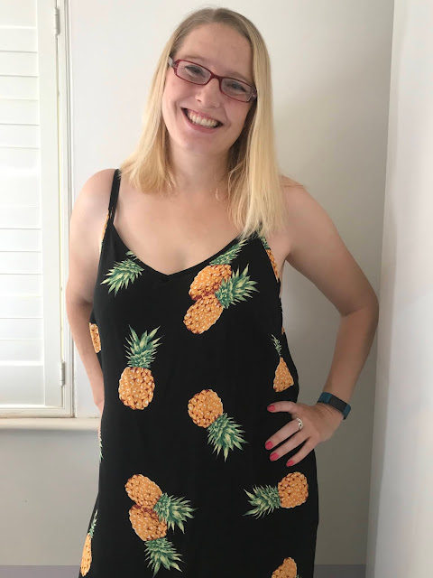 Smiling at the camera in a pineapple dress with a slight hint of bump
