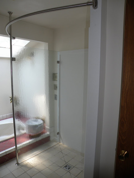 Enlarged shower after remodel. Tile on floor, solid surface and glass panel surround.