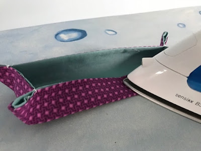 Using an iron to press the sides of a fabric tray together