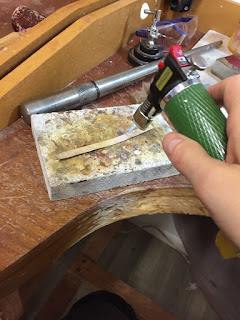 A blow torch annealing a flat piece of silver jewellery