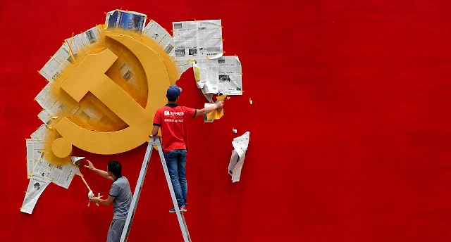 Workers peel papers off a wall as they re-paint the Chinese Communist Party flag on it at the Nanhu revolution memorial museum in Jiaxing, Zhejiang province May 21, 2014. REUTERS/Chance Chan via GIGA Hamburg