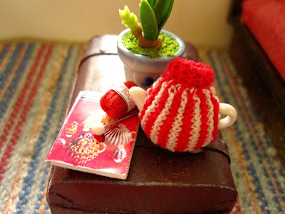 Modern dolls' house miniature trunk coffee table with a knitted tea cosy, knitting pattern, wool and a knitting needle on top.