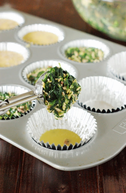 Spooning Make-Ahead Bacon & Spinach Quiche Cups Mixture in Muffin Cups Image