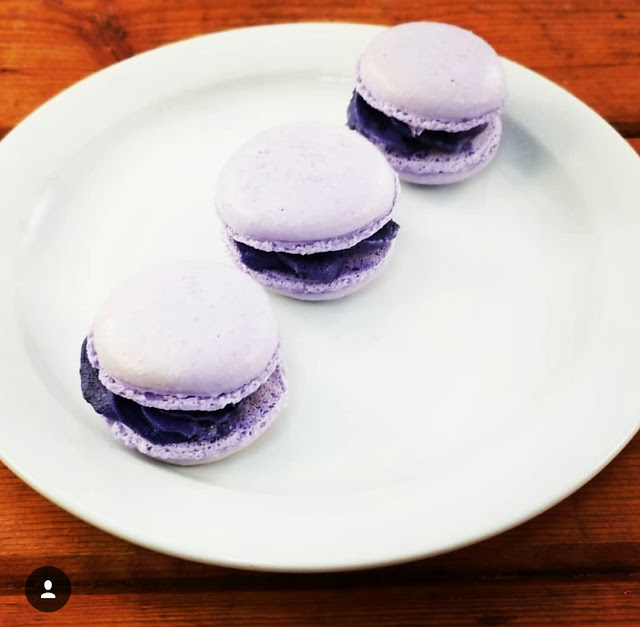 three blackcurrant macarons on a white plate