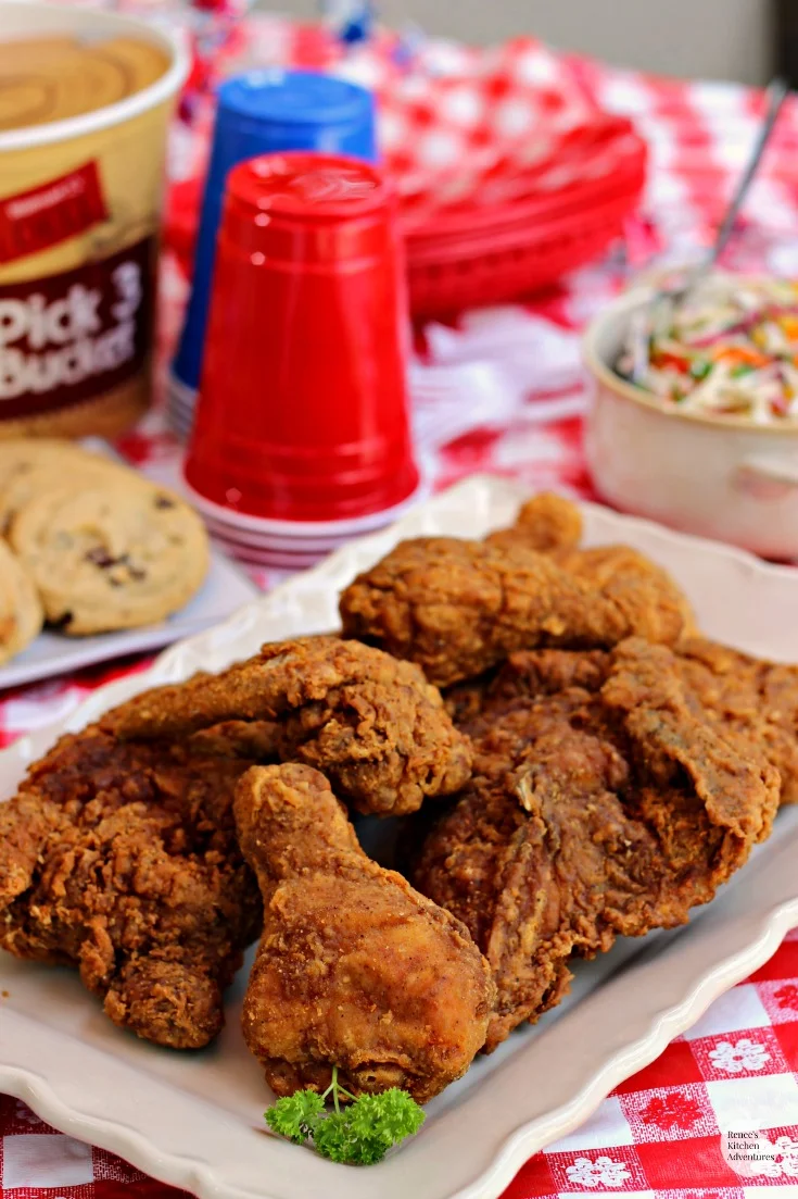 Firecracker Coleslaw by Renee's Kitchen Adventures and Fried chicken on a white platter sitting on a red and white checkered table cloth