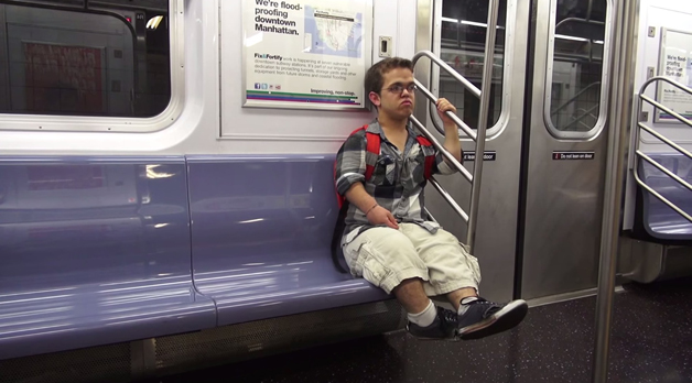 Foto de anão sentado no metrô