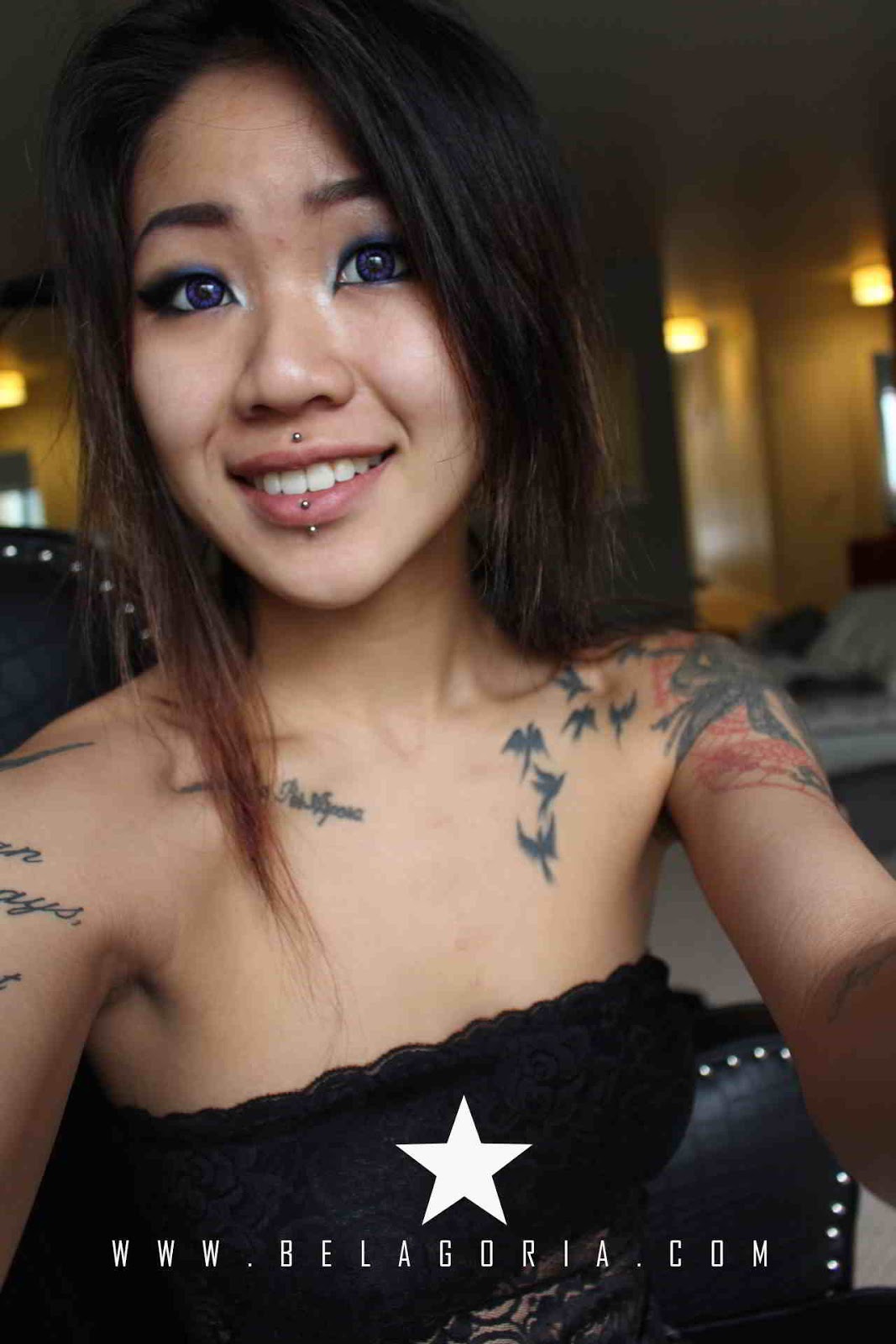 chica asiatica sonriendo, lleva tatuajes de libertad con pajaros