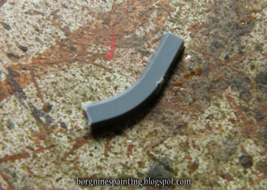 Photo showing a cut segment of a gray plastic sprue, slightly curving.