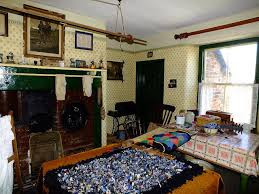 19th century or early 20th century living room, range fireplace, crowded with furniture, hanging washing airer, dark pictures on the walls, proggy rugs on the table.