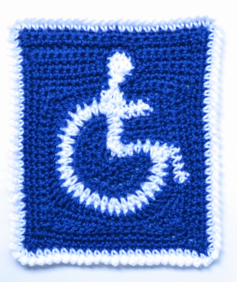 International Access Symbol (white wheelchair symbol on a blue background) created with crochet by Jodiebodie using a freeform technique to create the shapes and finished with a white crab stitch border. 