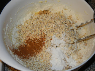 adding dry ingredients to the white bowl with eggs, butter, and sugar 