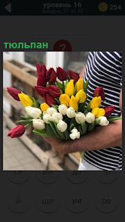 У девушки в руках находится большой букетов цветов тюльпанов