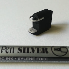 One-twelfth scale modern miniature 3D-printed Nespresso machine with silver highlights next to a silver caligraphy pen