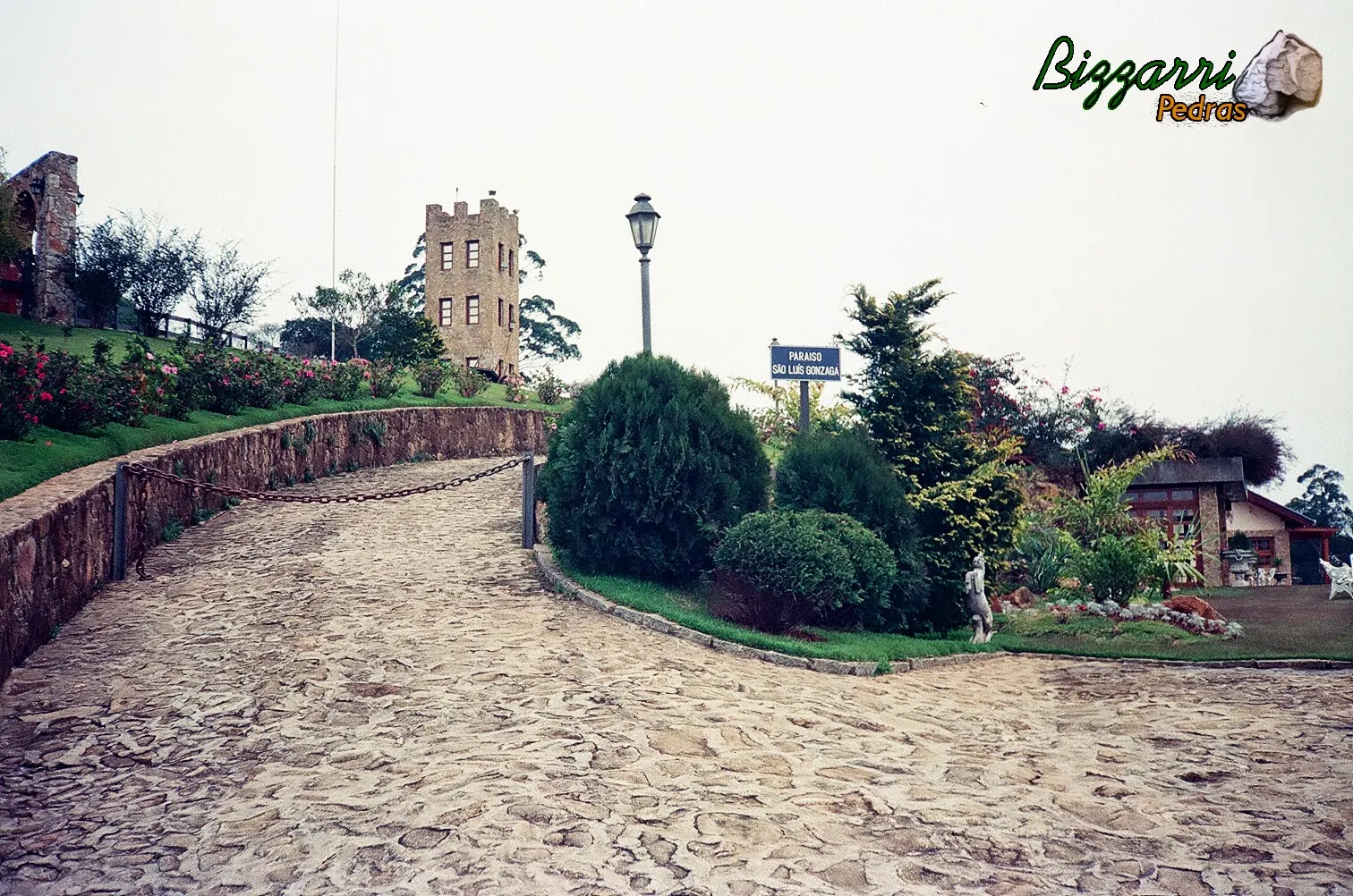 Na entrada do sítio em Mairiporã-SP o calçamento de pedra rústica com os muros de pedra, torre de pedra e o paisagismo.