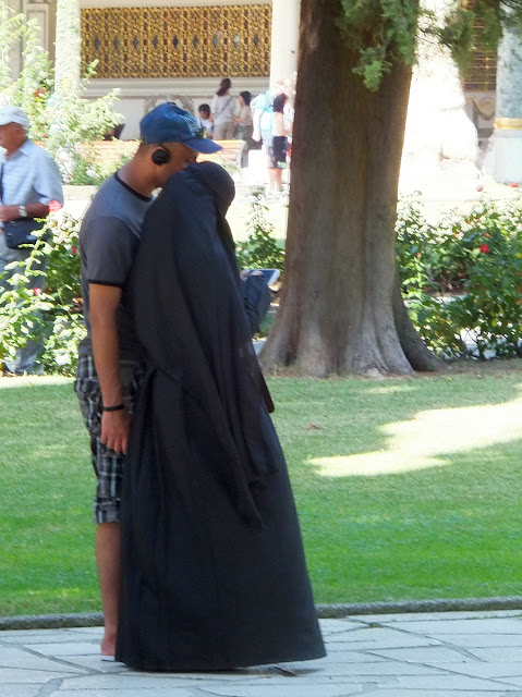 Парочка: парень в шортах с бейсболкой и девушка в чадре.