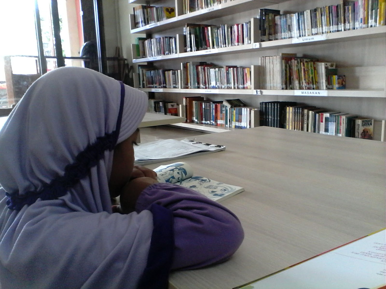 Syifa sedang asyik membaca buku di perpustakaan Syifa sedang asyik membaca buku di perpustakaan
