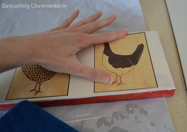 Hand applying rooster sticker to a sign