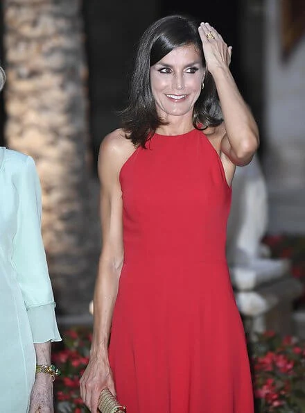 scoop neckline sleeveless fit and flare red dress. Dolce & Gabbana ready-to-wear collection, gold clutch. Queen Sofia