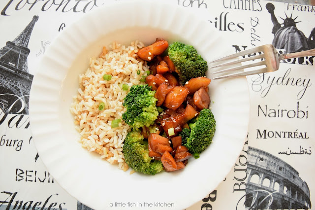 A white bowl is filled with rice, steamed broccoli and teriyaki chicken pieces.