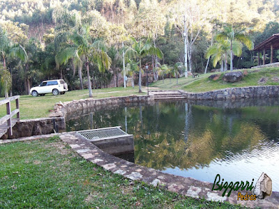 Construção do lago com muro de pedra, cascata de pedra no muro de pedra com a ponte de madeira, gramado com grama São Carlos em construção do lago em Piracaia-SP.