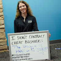 photo of a student holding up white board with her statement, I don't cheat because the struggle is part of the journey