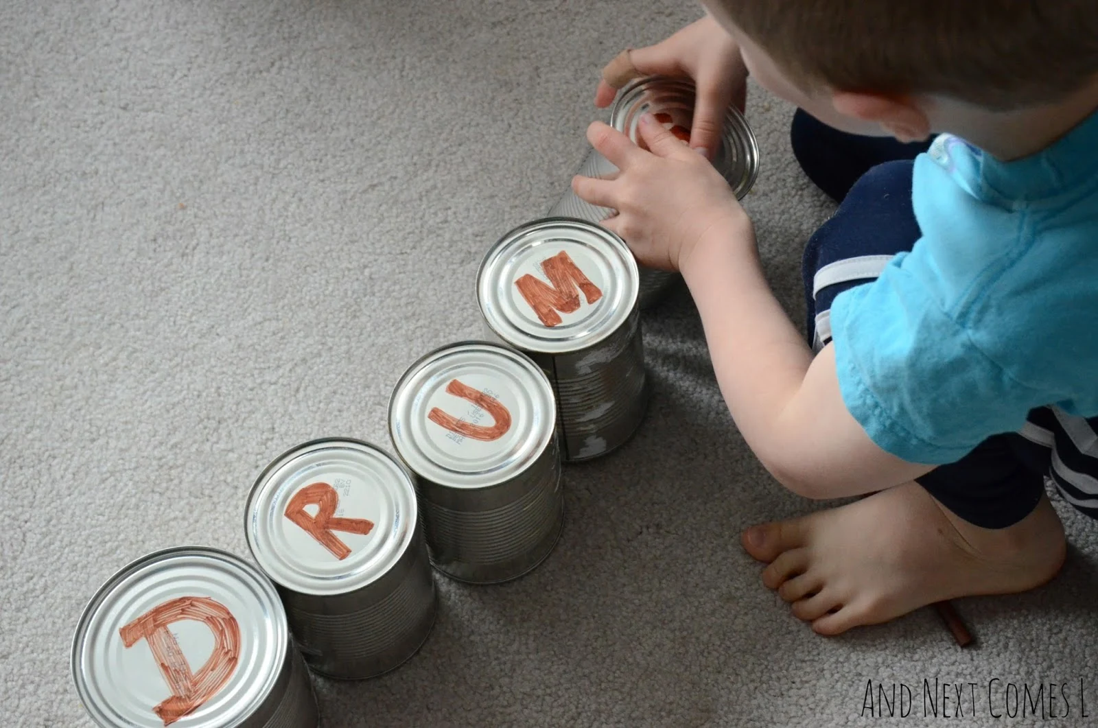 Spelling the word DRUMS with tin can drums from And Next Comes L