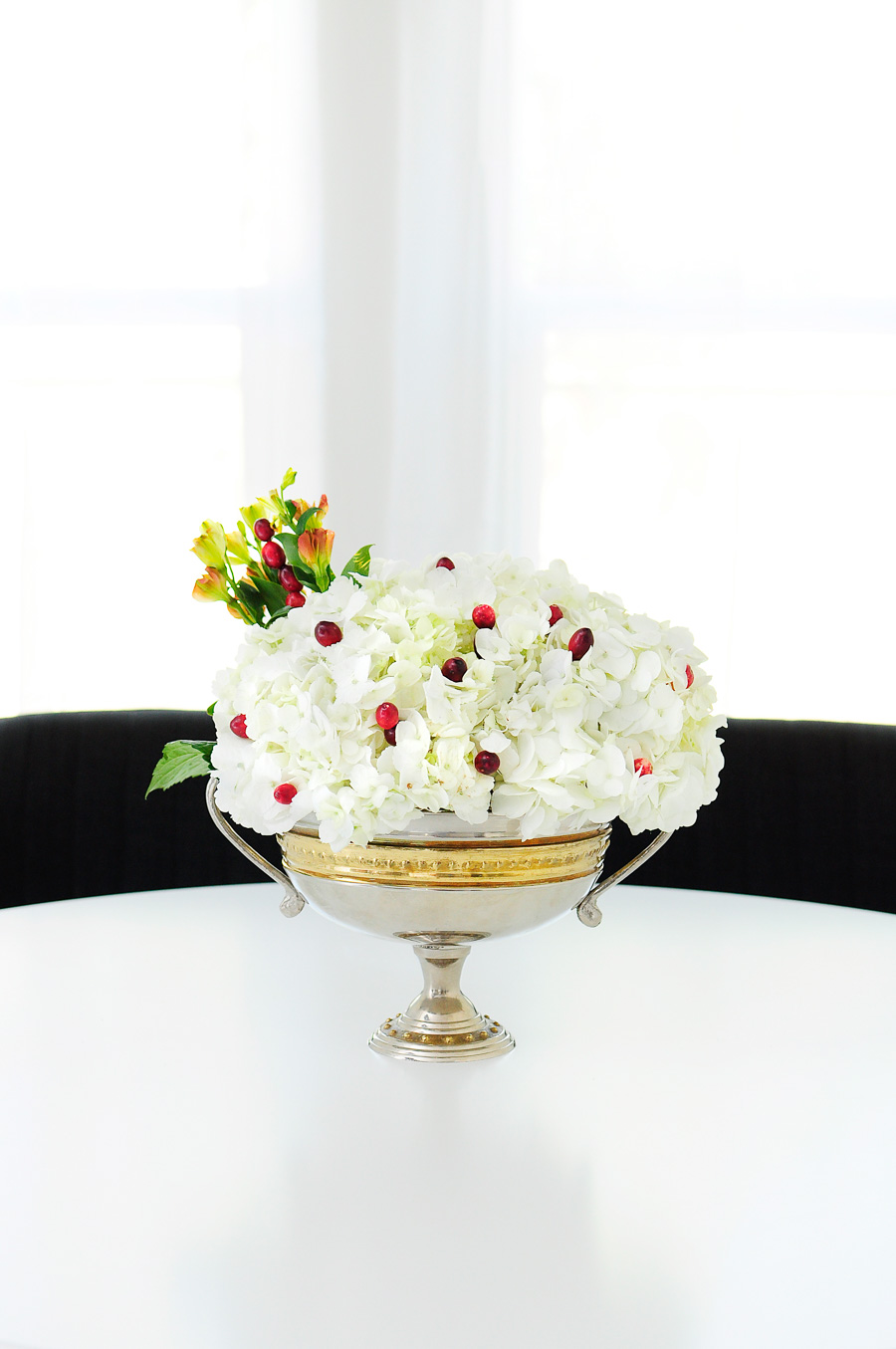 White hydrangeas paired with cranberries and greenery make a simple and elegant centerpiece for any holiday tablescape.