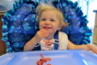 baby in high chair eating strawberries