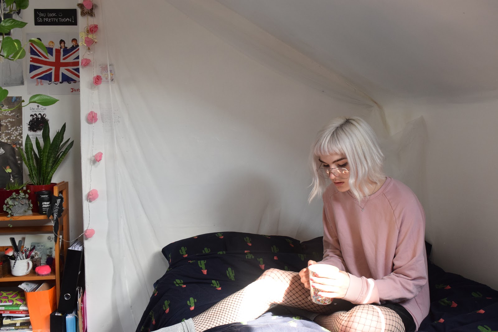 girl with silver hair sitting on a bed in a university bedroom