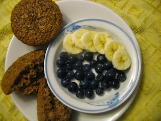 bran muffin with a bowl of yogurt topped with sliced bananas and blueberries 