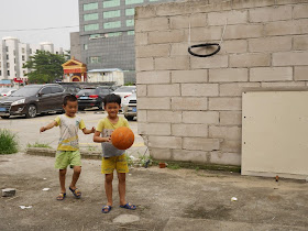 boys playing basketball with a hoop made out of a bicycle tire in Zhuhai, China
