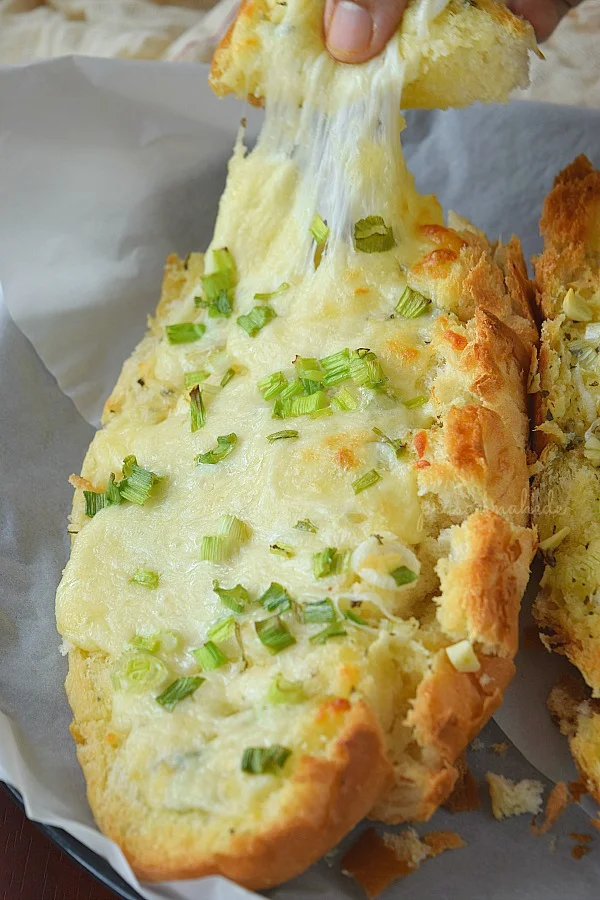 Delicious Cheese Garlic Bread topped with spring onion green served on a white paper
