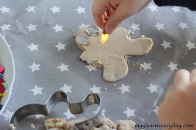 decorating a gingerbread play dough person with eyes