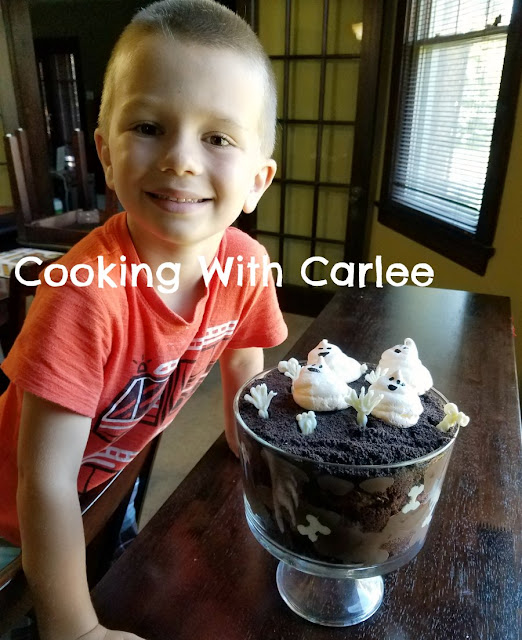 kid smiling next to his spooky masterpiece
