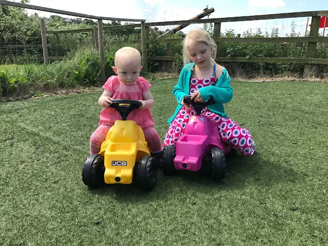 Children playing on pedal tractors at the farm in Essex