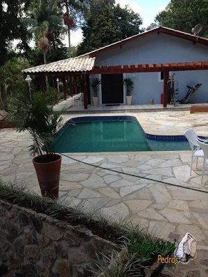 Construção da piscina em alvenaria com revestimento de azulejo, o piso do passeio da piscina com pedra São Tomé tipo caco em residência em Atibaia-SP com o pergolado de madeira.