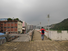man walking with outstretched arms on a wall bordering the Gui River (桂江) in Wuzhou (梧州)